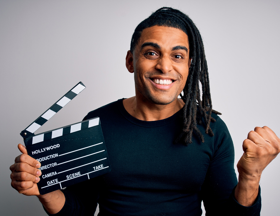 Young african american afro director man making movie using clapboard screaming proud and celebrating victory and success very excited, cheering emotion
